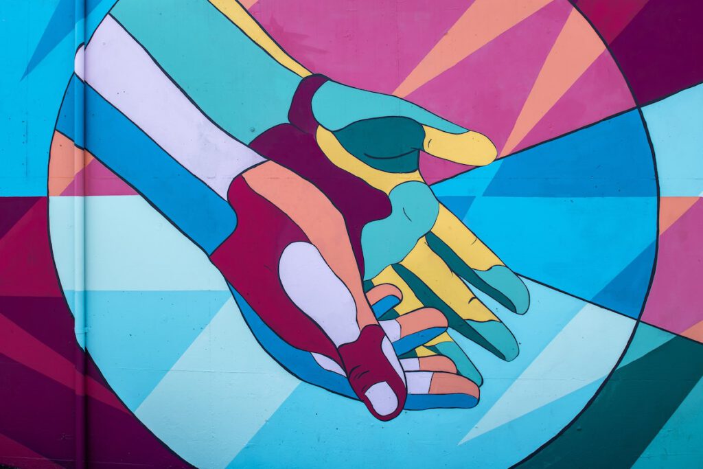 Feeling Disconnected From People: a mural of two hands open palm up with lots of colors