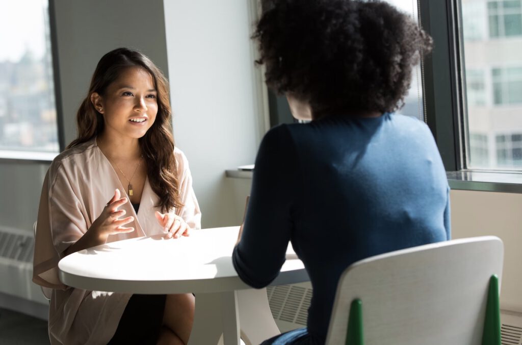 Two women talking at a table - sales conversation or interview