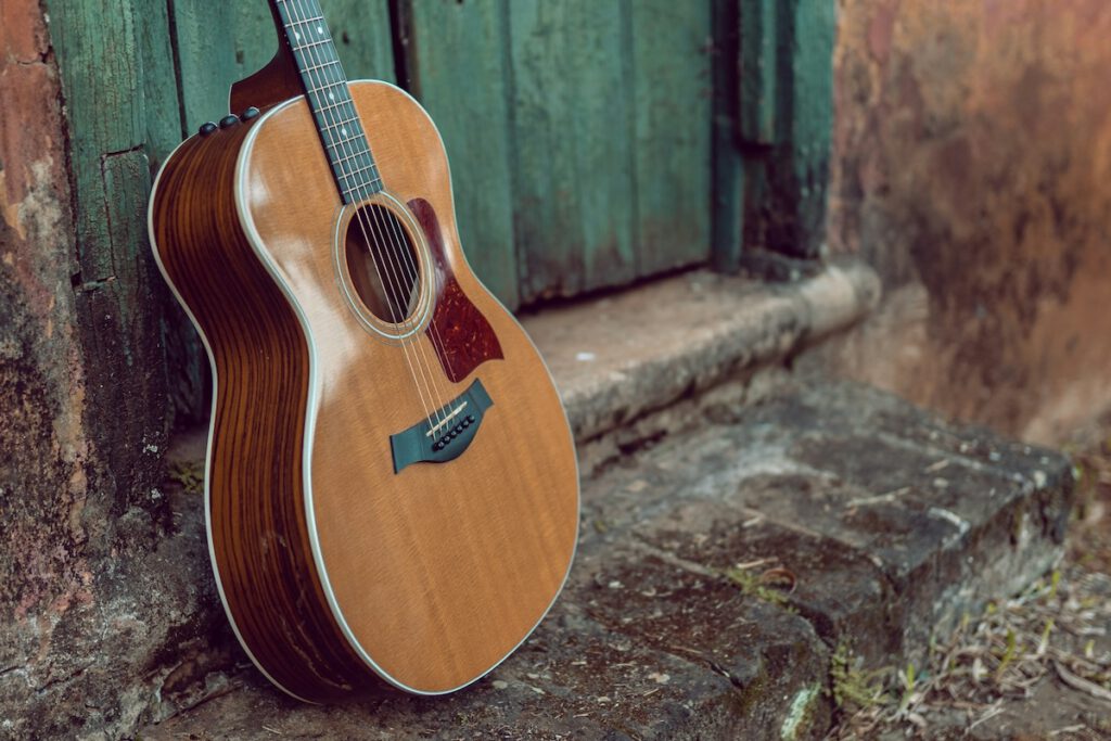 guitar leaning against a door in an alley