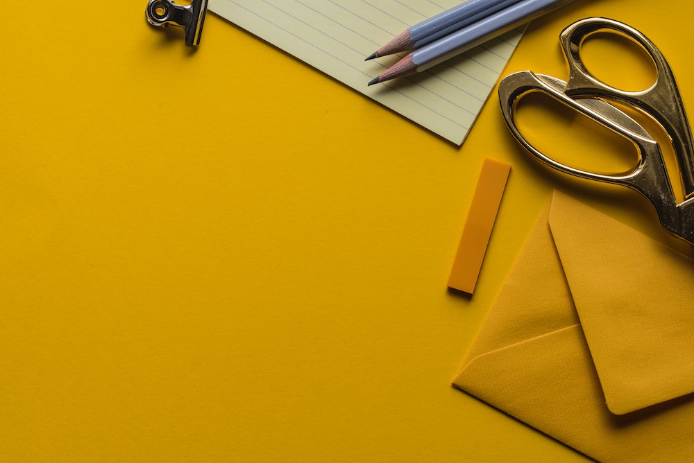 website color psychology - yellow table with yellow envelope, scissors, paper, and pencil