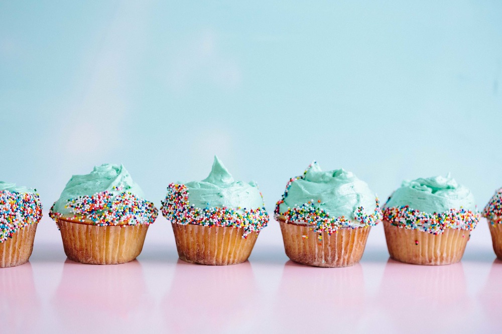 What Does Eat the Frog Mean? a row of rainbow sprinkled delicious cupcakes