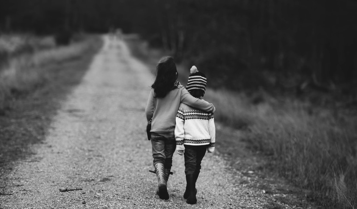 Self Care for Entrepreneurs: two young children walking down a dirt road arm in arm