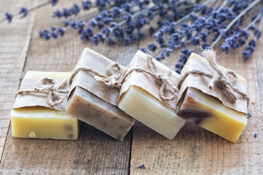 a collection of various soaps and lavender on a wooden table