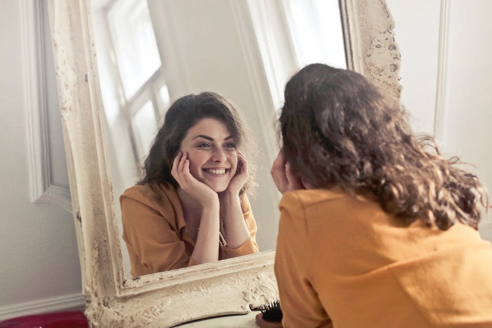 a woman looking at herself in the mirror and smiling